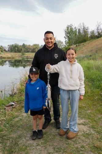 A family gathers for a photo with fish at the 2025 Tri-Cities Take Kids Fishing Day.